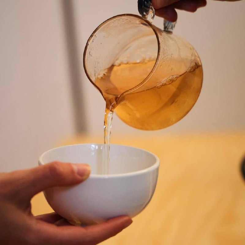 Pouring tea from a glass pitcher into a porcelain cup
